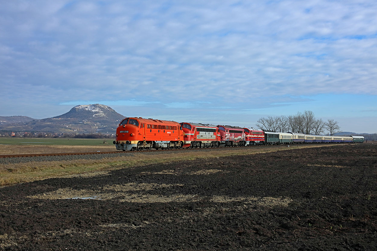 MNOS M61.019 + KV 459.021 + KV 459.022 + MAV M61.017 + 9 MNOS coaches (train Vulkan from Budapest Kelenfold to Tapolca via Aszofo) pass an expired vulcano at Tapolca on 30 December 2017.